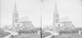 Modern Gothic church in open country, square tower and spire, statue of warrior with harp in foreground