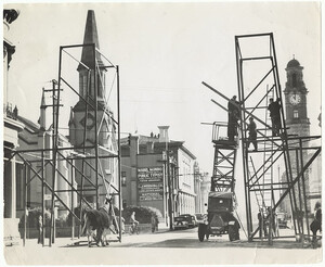View north down St John Street Launceston from Paterson Street corner, with men erecting V day arch.  Photograph by Burrows (1946)